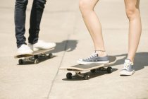 Jambes de skateboarders féminins et masculins debout dans le skatepark — Photo de stock