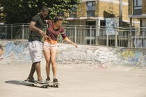 Jeune homme et femme pratiquant le skateboard équilibre dans le skatepark — Photo de stock
