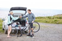 Cyclists preparing bicycle for ride in field — Stock Photo