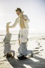 Padre ayudando a los hijos con handstand en la playa - foto de stock