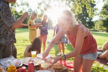 Young woman selecting food at group party picnic in park — Stock Photo