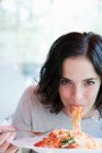 Mulher comendo espaguete e olhando para a câmera — Fotografia de Stock