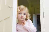 Female toddler peering from door — Stock Photo