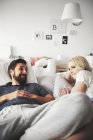 Lächelndes junges Paar entspannt im Bett — Stockfoto