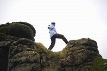 Vista a basso angolo della donna sulla formazione rocciosa, Dartmoor, Devon, Regno Unito — Foto stock