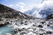 Montanhas cobertas de neve e fluxo de rio rochoso — Fotografia de Stock