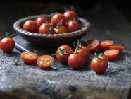 Fresh organic tomatoes in bowl and on table — Stock Photo