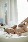 Desnudo bebé niño acostado en cambiador mat patadas sus piernas - foto de stock