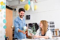 Female and male designer laughing at twig leaves in printing press studio — Stock Photo