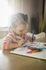 Criança feminina à mesa desenho em caderno de esboços — Fotografia de Stock