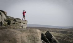 Corredor masculino fotografiando desde la cima de Stanage Edge, Peak District, Derbyshire, Reino Unido - foto de stock