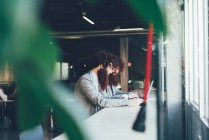 Близнецы-хипстеры, работающие на ноутбуке в офисе — стоковое фото