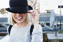 Portrait of blonde haired woman wearing hat over eyes smiling — Stock Photo
