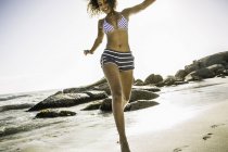 Прыгающая женщина на пляже — стоковое фото
