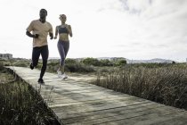 Paar joggt auf Holzsteg — Stockfoto
