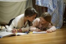 Duas irmãs deitadas no chão do quarto desenho em cadernos de esboços — Fotografia de Stock