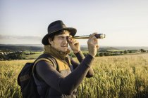 Mid adult man, standing in field, looking through telescope, Neulingen, Baden-W?rttemberg, Germany — Stock Photo