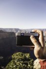 Mão macho segurando câmera de filme retro com paisagem canyon — Fotografia de Stock