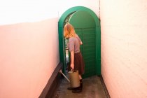 Молодая женщина, несущая поливающую дверь в сад — стоковое фото