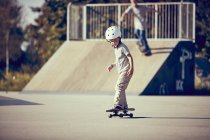 Niño pequeño en el casco de skate en el parque - foto de stock
