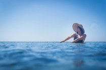 Jovem mulher usando chapéu de sol vadear em mar azul profundo, Villasimius, Sardenha, Itália — Fotografia de Stock