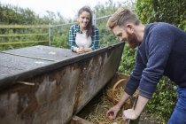 Young couple collecting eggs from chicken coop — Stock Photo