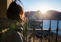 Elevated over shoulder view of woman looking out over coast at sunset, Italy — Stock Photo