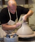 Мужчина гончар формирования глиняный горшок на гончарном круге в мастерской — стоковое фото