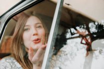 Couple in passengers seat of car, woman blowing kiss — Stock Photo