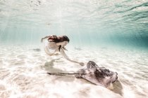Female free diver swimming with stingray on seabed — Stock Photo