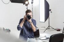 Les tests de photographe masculin se concentrent sur les reflex numériques dans le studio de photographie — Photo de stock