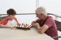 Дідусь і онук грають у шахи разом — стокове фото
