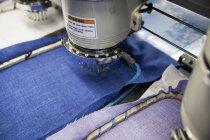 Programmierte Stickmaschinen beschleunigen das Nähen blauer und lila Stoffe in der Bekleidungsfabrik — Stockfoto