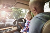Over shoulder view of daughter sitting on father lap driving car — Stock Photo
