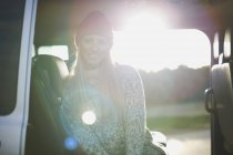 Retrato iluminado do sol da jovem mulher sentada na parte de trás do carro — Fotografia de Stock