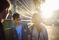 Young adult friends talking on sunlit street — Stock Photo
