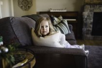 Menina com medo olhando para os lados do sofá — Fotografia de Stock