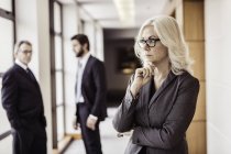Бізнес-леді з рукою на підборідді в офісному коридорі — стокове фото