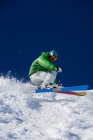 Man in green carving downhill. — Stock Photo