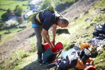 Scalatore di roccia sul fianco della collina che prepara attrezzatura da arrampicata — Foto stock