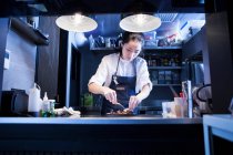 Asiatischer Koch in der Großküche bei der Essenszubereitung — Stockfoto