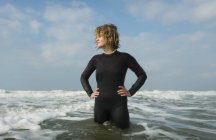 Chica de pie en el Mar del Norte vistiendo traje de neopreno - foto de stock