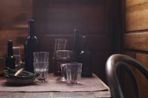 Verres vides et bouteilles sur table en bois — Photo de stock