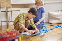Two young boys playing with toy train set — Stock Photo
