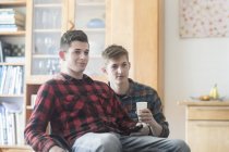 Young man using wheelchair watching tv with friend in kitchen — Stock Photo