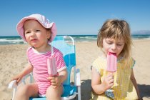 Femme tout-petit et soeur manger des sucettes de glace sur la plage — Photo de stock