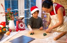 Mujer madura preparando galletas de Navidad con hijo en el mostrador de la cocina - foto de stock