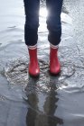 Person wearing rubber boots standing in puddle — Stock Photo