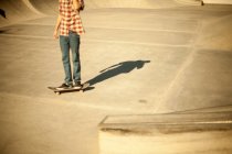 Skateboarder in sun lighted skate park, cropped shot — Stock Photo