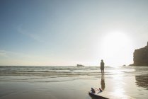 Senior woman surfer standing looking out to sea, Camaret-sur-mer, Bretaña, Francia - foto de stock